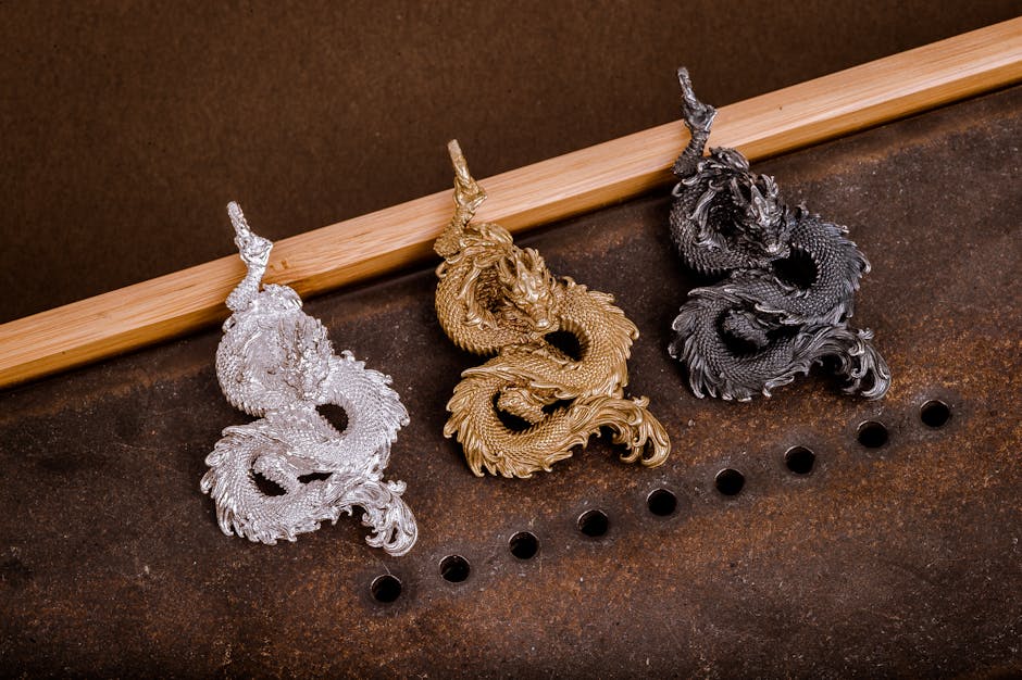A stunning display of silver, gold, and black dragon-shaped metal pendants on a textured surface.