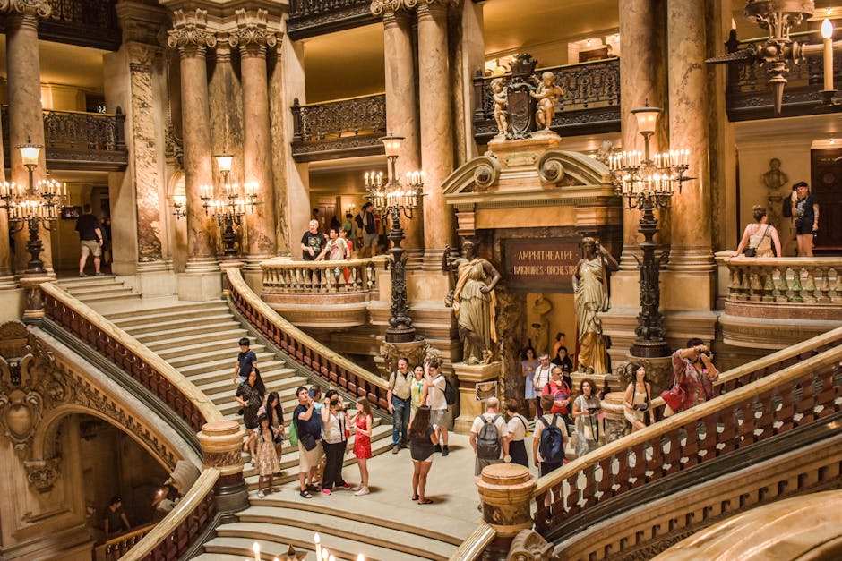 Tourists admire the grand staircase inside Palais Garnier, a famous landmark in Paris, France.