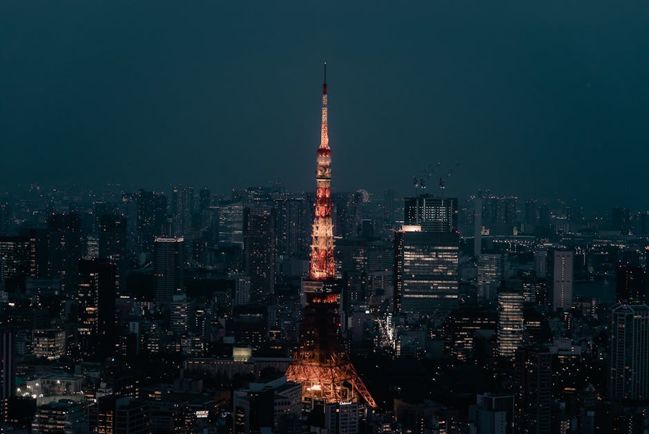 Stunning view of Tokyo Tower lit up at night, surrounded by the urban skyline of Minato City, Tokyo.